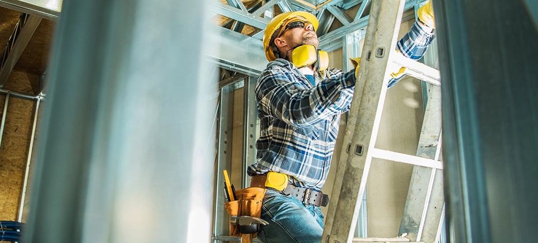 A construction worker climbs a ladder.